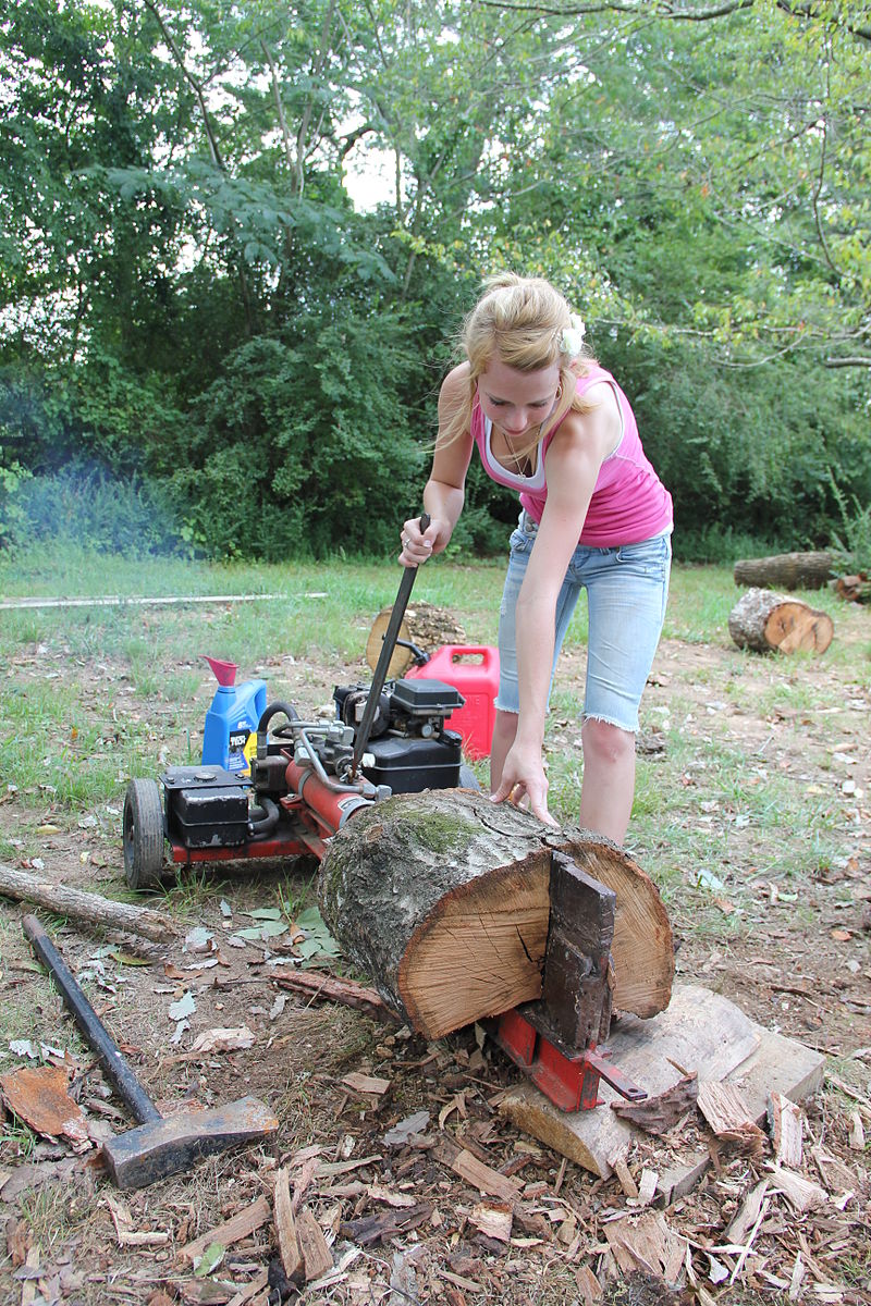 Woman splitting logs and showing gas powered log splitter parts